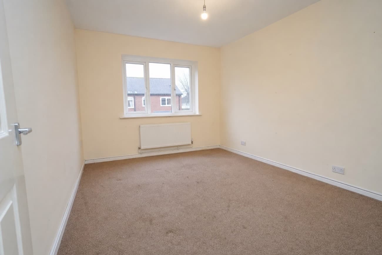 Before: the empty room photographed from the doorway, bare walls and carpet under a single bulb