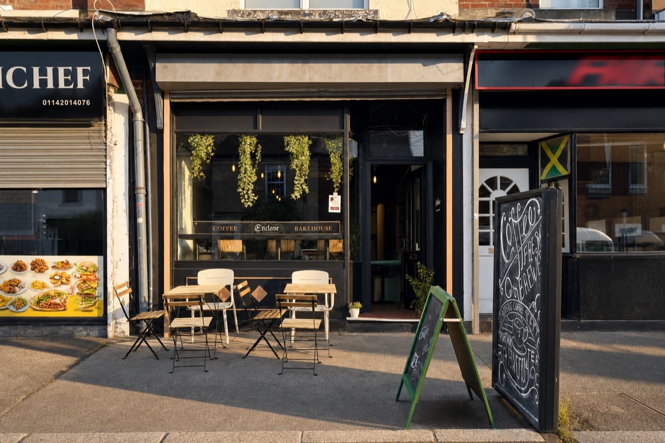 After: the same shopfront, neighbours and outside tables in warm low evening sun, straightened and cropped in to the building