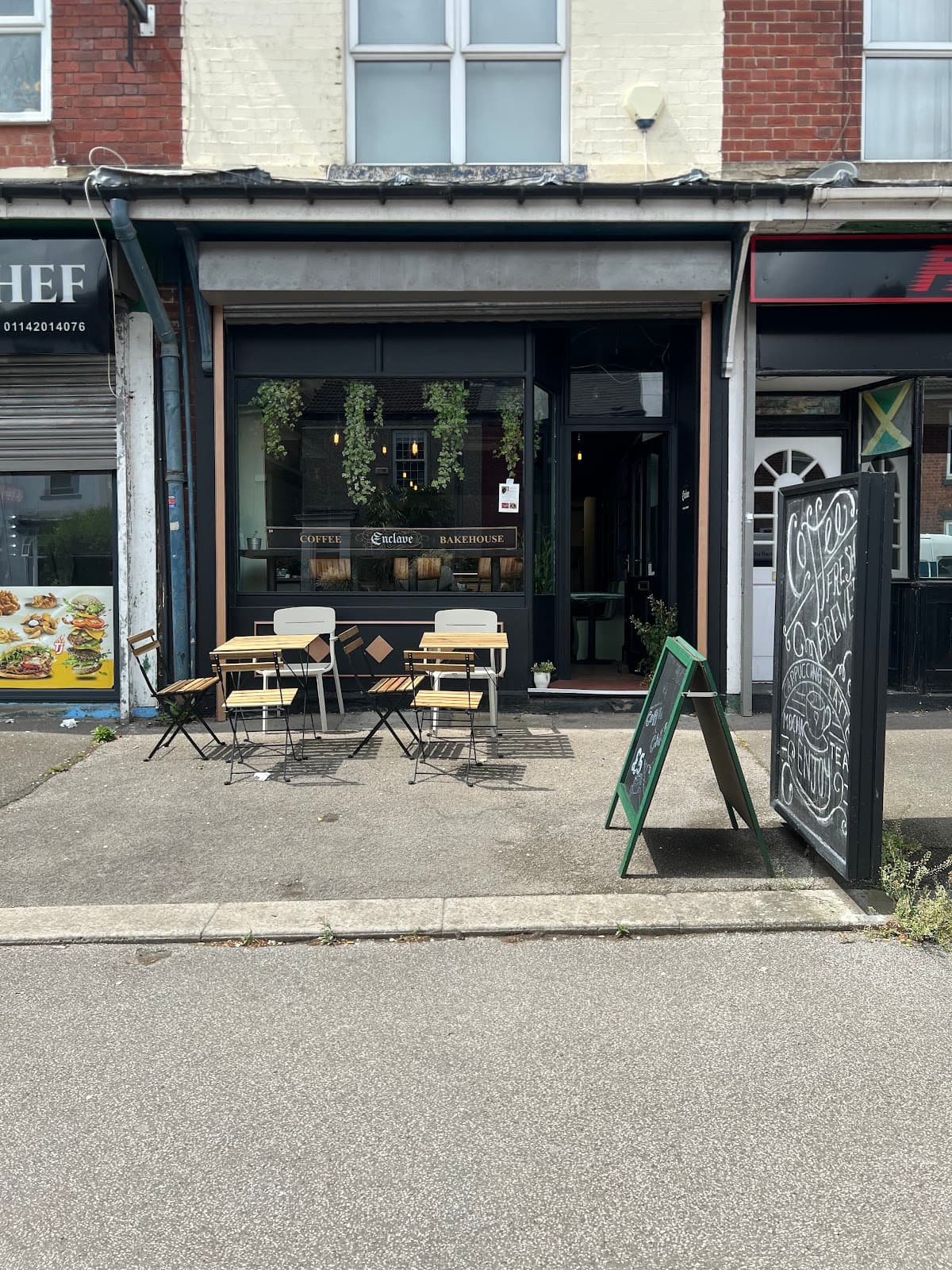 Before: a portrait phone photo of the Enclave shopfront on an overcast day, slightly crooked, with cafe tables outside and a wide strip of empty road in the foreground