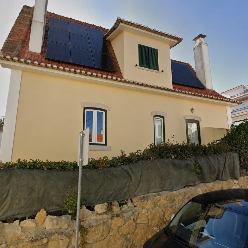 The same photo of the house, now with black solar panels on the roof