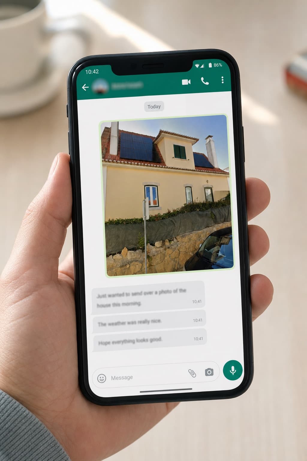 A hand holding a phone with the rendered house open in a WhatsApp chat
