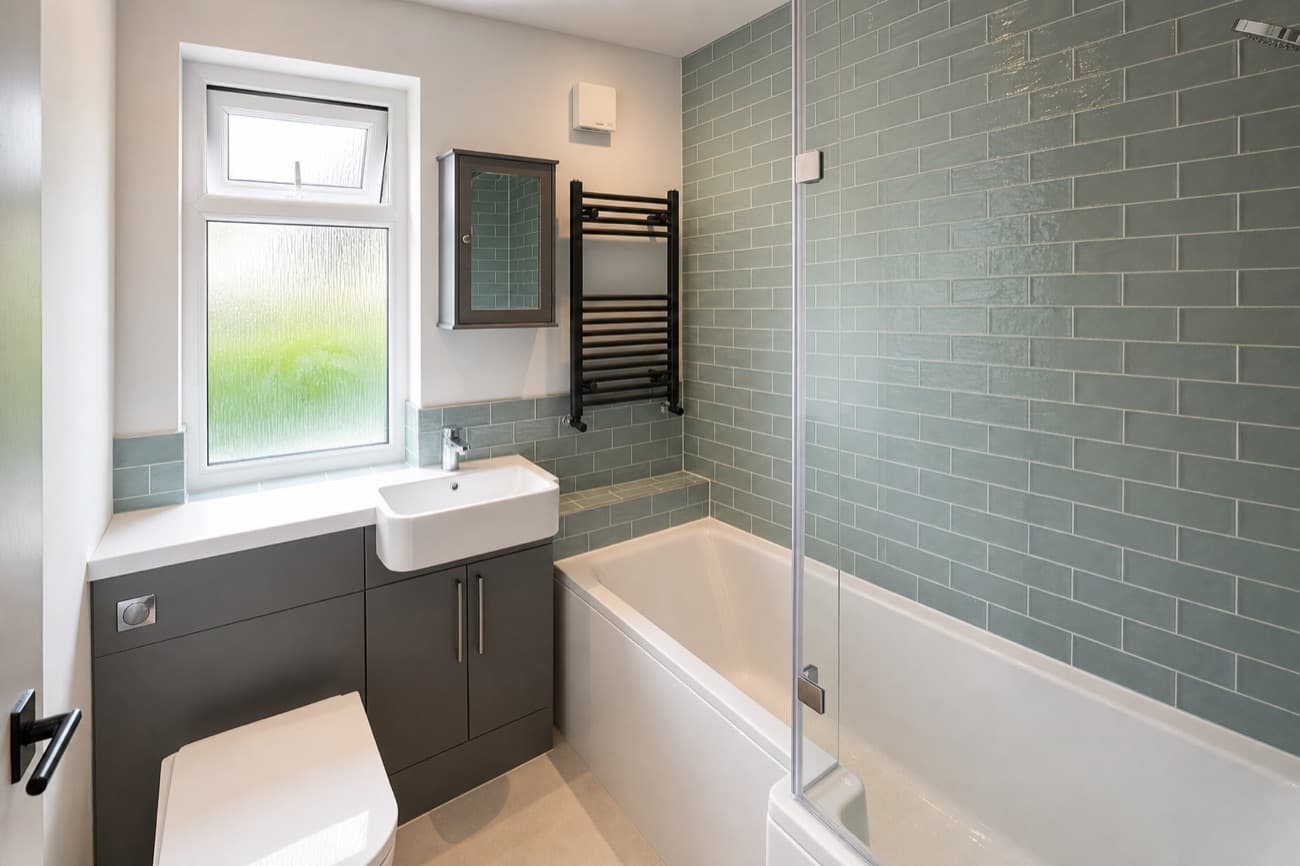After: the same bathroom in soft window daylight, verticals straight, the spray bottles gone