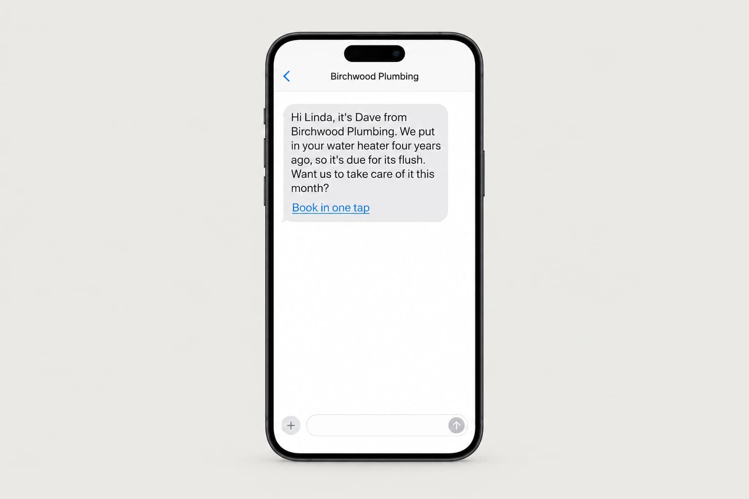 A phone showing a text from Birchwood Plumbing: Hi Linda, it's Dave from Birchwood Plumbing. We put in your water heater four years ago, so it's due for its flush. Want us to take care of it this month? followed by a Book in one tap link